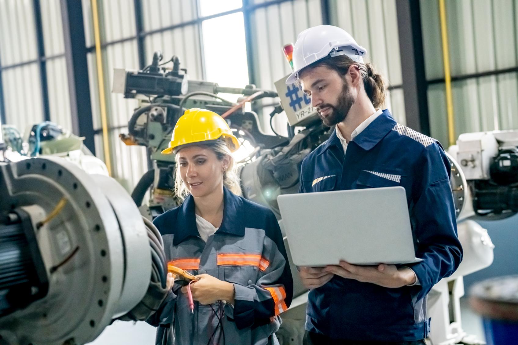 Engineers analyzing industrial machinery data using Industrial IoT technology on a factory floor.